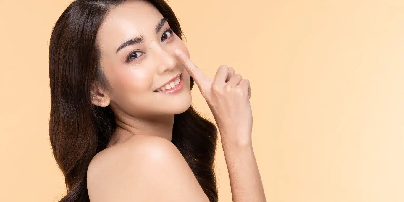 Best Time to Get a Nose Job for Faster Healing and Minimal Swelling woman touching nose smile with clean and fresh skin