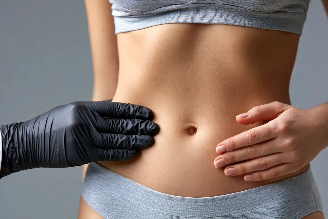 Abdominal Examination Consultation A doctor wearing black gloves examining a womans abdomen area during a consultation